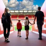 Anfield Stadium - Tunnel Family of four standing in the players tunnel at Anfield Stadium, looking out towards the pitch and Kop stand
