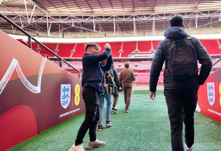 A young boy and his father walk out of the tunnel at Wembley Stadium during a tour