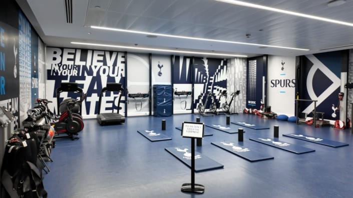 Tottenham Hotspur Players' Training and Recovery Facility Modern training room with exercise equipment and Spurs motivational wall art