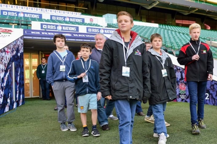 Young rugby fans on Twickenham Stadium tour pitch side